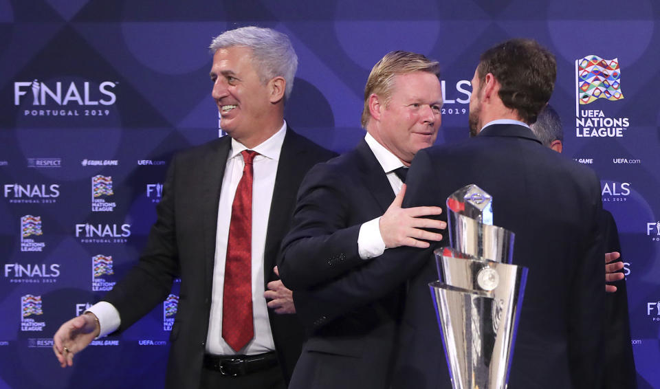 Netherlands soccer team manager Ronald Koeman, center, embraces England manager Gareth Southgate, as Switzerland manager Vladimir Petkovic looks on at a press conference after the UEFA Nations League Finals draw at the Shelbourne Hotel, Dublin, Monday Dec. 3, 2018. (Niall Carson/PA via AP)