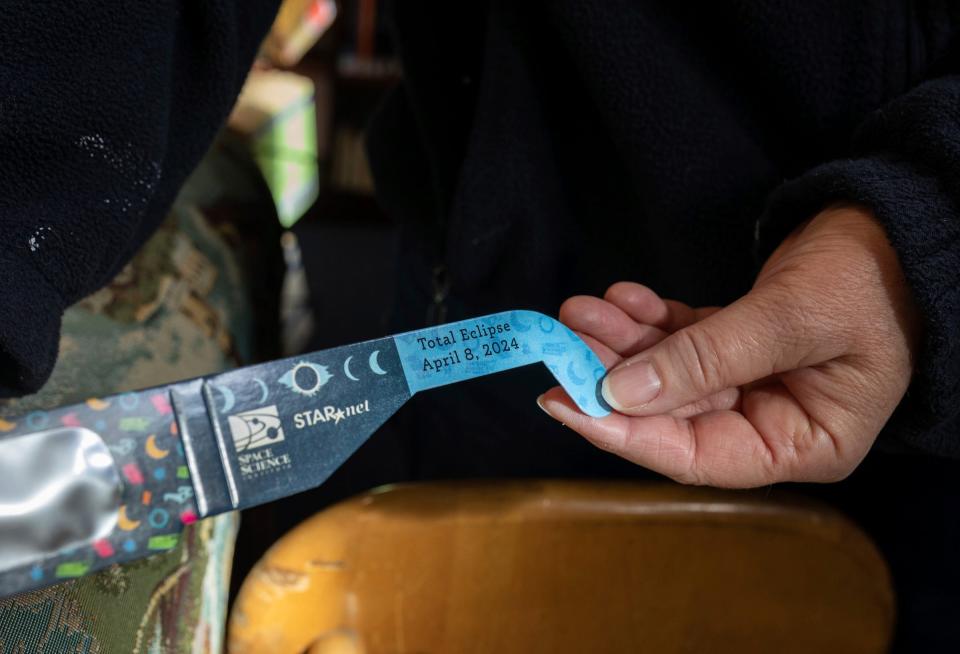 Becky Poca, a library clerk with the Rasey Memorial Branch Library, or as many locals know it as Luna Pier Library, holds a pair of solar eclipse glasses inside the library on Thursday, March 7, 2024.