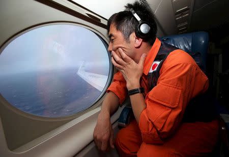 Crew member Koji Kubota of the Japan Coast Guard looks out of an observation window aboard the Japan Coast Guard Gulfstream V aircraft as it flies over the southern Indian Ocean looking for debris from missing Malaysian Airlines Flight MH370, in this April 1, 2014 file photo. REUTERS/Paul Kane/Pool/Files