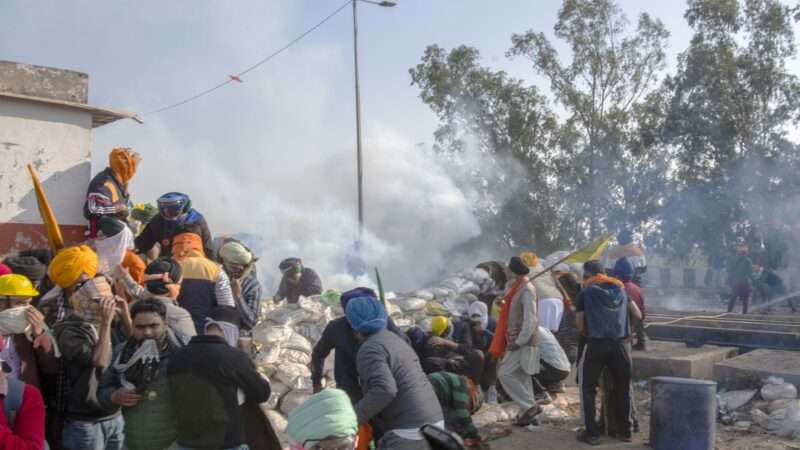 Protesting farmers run away from tear gas shells used by the police near Shambhu border that divides northern Punjab and Haryana states, some 200 kilometers (120 miles) from New Delhi, India, Wednesday, Feb.21, 2024. The protesting farmers began their march to the Indian capital last week, but their efforts to reach the city have been blocked by authorities.