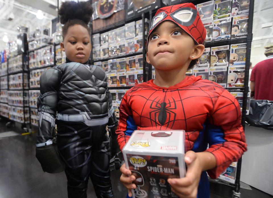 Dressed as Black Panther, left, Svante Chapman, 7, watches his cousin Valencio Cooley, 4, show his mother a toy Spiderman during Comicon Erie inside the Bayfront Convention Center in2022.