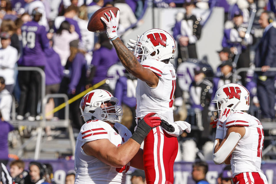 Wisconsin offensive lineman Tanor Bortolini, left, lifts wide receiver Skyler Bell, center, after Bell scored a touchdown against Northwestern during the first half of an NCAA college football game on Saturday, Oct. 8, 2022, in Evanston, Ill. (AP Photo/Kamil Krzaczynski)