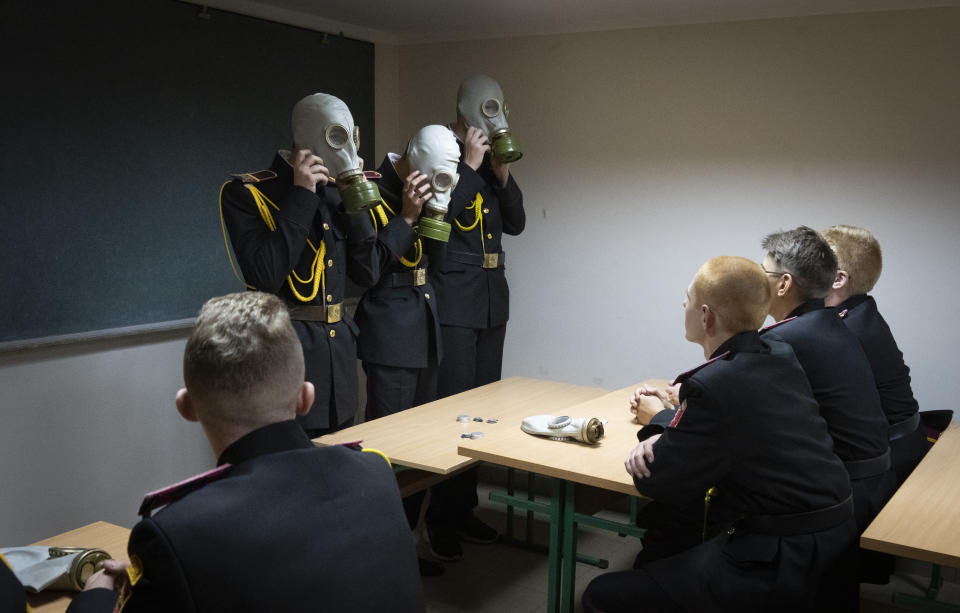 Tres cadetes practican el uso de máscaras antigás durante una lección en un refugio antiaéreo el primer día de clases en un liceo colegio militar en Kiev, Ucrania, el 1 de septiembre de 2022. (AP Foto/Efrem Lukatsky)