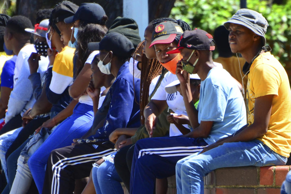 Without practicing social distancing people queue for social grant payments at a post office in Port Elizabeth, South Africa, Friday, Nov. 13, 2020. The African continent has surpassed 2 million confirmed cases of COVID-19 as health officials warn of infections starting to creep up again into a second surge. (AP Photo/Theo Jeptha)