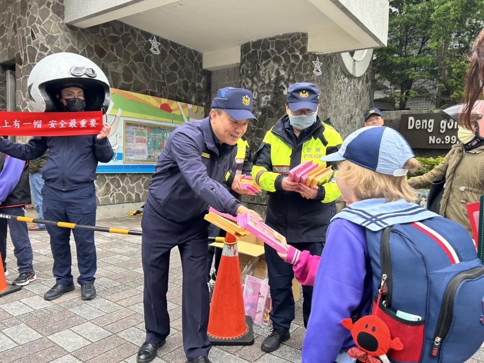 淡水警分局長彭正中於校門口發放小禮品給學童。（記者徐煜勝翻攝）