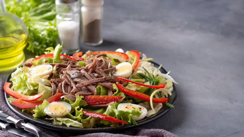 A steak salad on a black plate