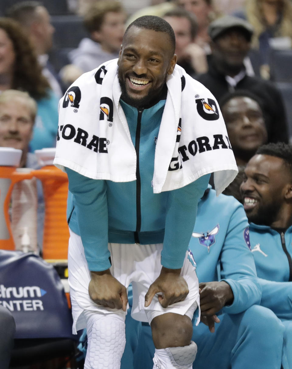 FILE - In this March 26, 2019, file photo, Charlotte Hornets' Kemba Walker laughs at a play from the bench during the first half of an NBA basketball game against the San Antonio Spurs in Charlotte, N.C. The three-time All-Star point says he’d be willing to work with the Hornets and take less than the “supermax” $221 million contract he’s eligible to receive to re-sign with Charlotte. (AP Photo/Chuck Burton, File)