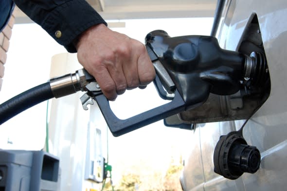 Close up of a customer's hand pumping fuel into car's gas tank.