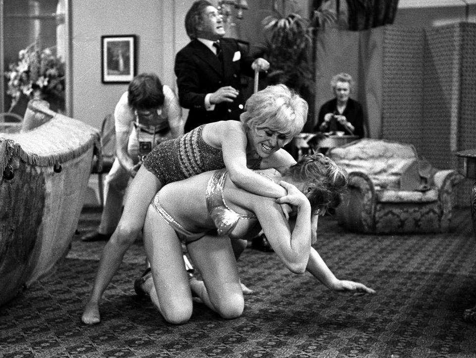 English actors Peter Butterworth and Robin Askwith watch feuding actresses Margaret Nolan and Barbara Windsor in the film 'Carry On Girls', 1973. (Photo by Larry Ellis Collection/Getty Images)