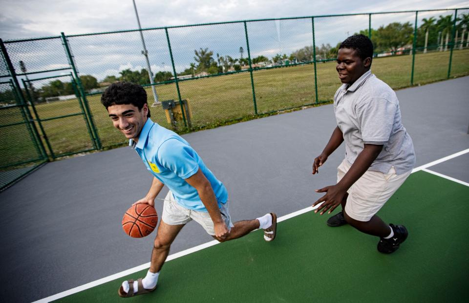 Gabriel Dahan, treasurer, CRAM or Creating Role Models and Mentors, left plays basketball with Fort Myers Middle Academy student Itzblayneson St. Hilaire during an afterschool session at the school in March 6.