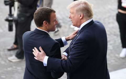 US President Donald Trump (R) and French President Emmanuel Macron shake hands at the end of the annual Bastille Day military parade on the Champs-Elysees  - Credit: Alain Jocard/AFP