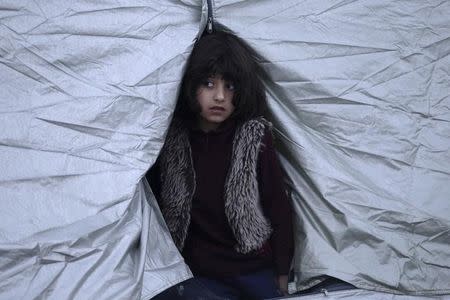 A girl looks out from a tent at a relocation camp where stranded refugees and migrants wait to cross the Greek-Macedonian border, near the Greek village of Idomeni, March 1, 2016. REUTERS/Alexandros Avramidis