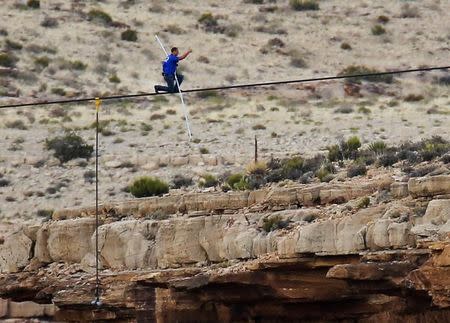 Daredevil Nik Wallenda gives a thumbs-up sign as he nears the end, after walking on a two-inch (5-cm) diameter steel cable rigged 1,400 feet (426.7 metres) across more than a quarter-mile deep remote section of the Grand Canyon near Little Colorado River, Arizona June 23, 2013. REUTERS/Mike Blake