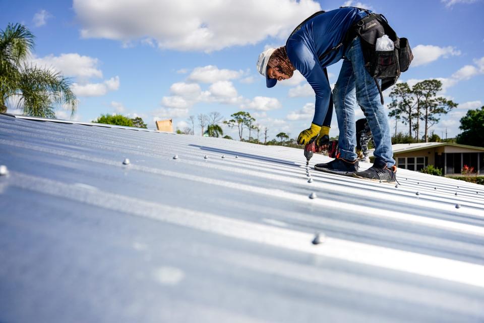 Roofers replace an old roof on Monday, Feb. 21, 2022, at Indianwood Golf and Country Club in Indiantown. Homeowners insurance premiums have increased 25% this year and many insurers are not writing policies for roofs over 15 years old.