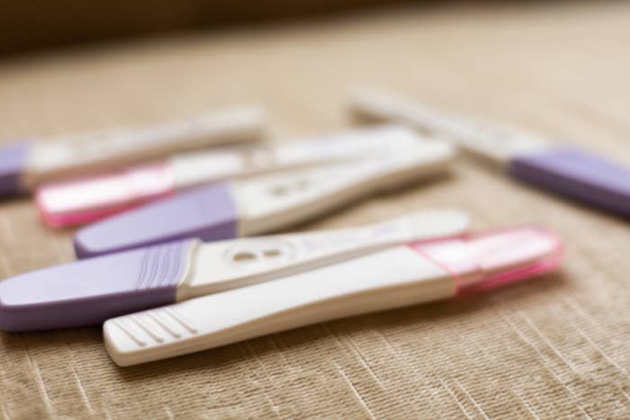 Several home pregnancy tests are laid out on a surface, some showing results