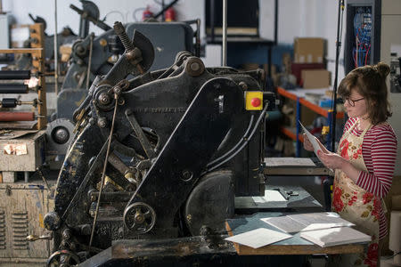 Lottie Small use the die stamping press at the workshop of Barnard and Westwood, who are printing the invitations for Britain's Prince Harry and Meghan Markle's wedding at Windsor Castle in May, London, Britain, March 22, 2018. Victoria Jones/Pool via Reuters