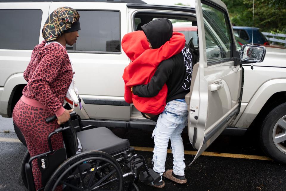 Damontrae Allen, 14, lifts his older brother, Damarion, out of the family car.