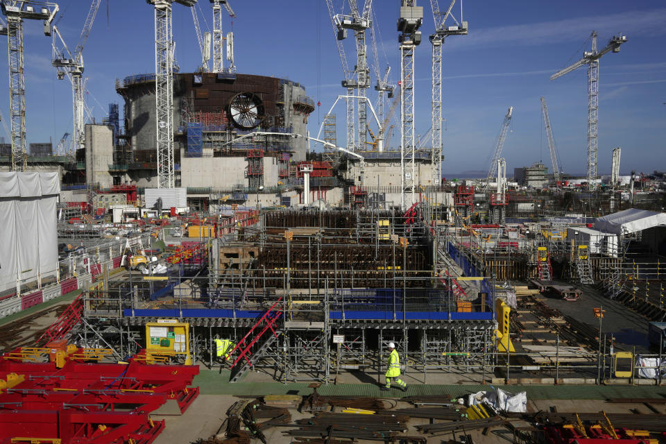 An employee walks at the Hinkley Point C nuclear power station construction site in Somerset, England, Tuesday, Oct. 11, 2022. The Hinkley Point C project is estimated to cost up to 26 billion pounds ($30 billion) and is set to be completed in 2027. (AP Photo/Kin Cheung)