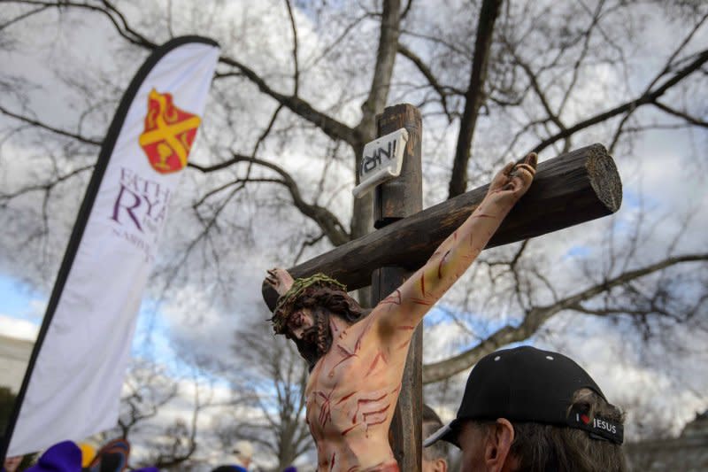 An abortion opponent holding a crucifix passes in front of the U.S. Supreme Court during the March for Life on the National Mall in Washington last year. The Catholic Conference of Bishops fears increasing rhetoric over abortion rights endangers houses of worship. File Photo by Bonnie Cash/UPI