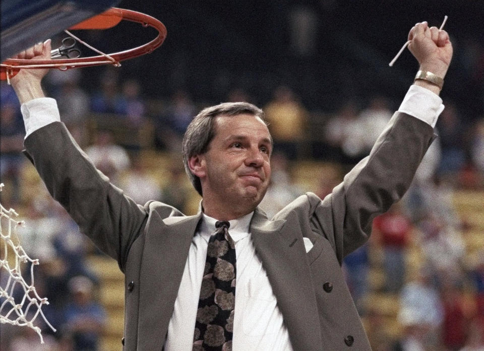 FILE - In this March 27, 1993, file photo, Kansas coach Roy Williams raises his arms in victory after cutting a piece of the net after the NCAA Midwest Regional final in St. Louis. Williams' Jayhawks defeated Indiana 83-77 to advance to the Final Four in New Orleans. Williams paid tribute Wednesday, Sept. 9, 2020, to Gene Budig, a day after the former American League president and head of three major universities died at 81. “He was the guy that gave Roy Williams a chance,” Williams told The Associated Press. “He made it OK for the athletic director to hire this no-name assistant coach from North Carolina as the head basketball coach at the University of Kansas.” (AP Photo/Seth Perlman, File)