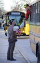 A runner in the 118th Boston Marathon shakes the hand of a spectator holding American flags as runners' busses arrive near the start line Monday, April 21, 2014 in Hopkinton, Mass. (AP Photo/Stephan Savoia)