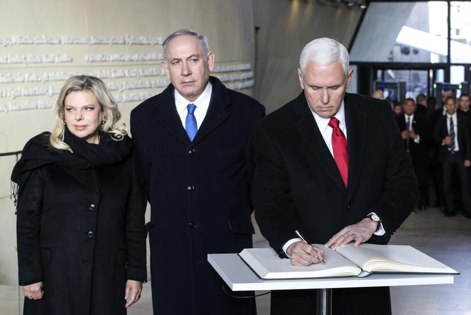 United States Vice President Mike Pence writes in the guest book beside Israeli Prime Minister Benjamin Netanyahu and his wife Sara, at the Monument to the Ghetto Heroes after a wreath laying ceremony in Warsaw, Poland, Thursday, Feb. 14, 2019. The Polish capital is host for a two-day international conference on the Middle East, co-organized by Poland and the United States. (AP Photo/Michael Sohn)