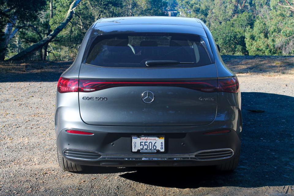 A gray Mercedes-Benz EQE electric SUV in a gravel parking lot. 