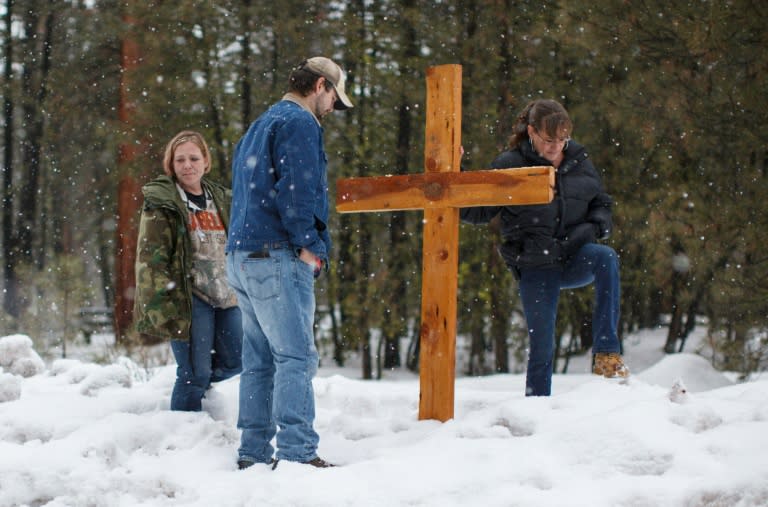 Mourners stand near a wooden cross on Highway 395 near Burns, Oregon on January 29, 2016, at the location where Robert "LaVoy" Finicum was shot dead and others were arrested