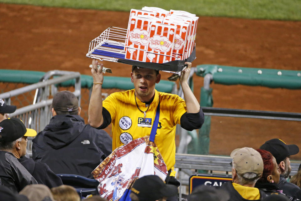 FILE - In this April 29, 2016, file photo, a popcorn and Cracker Jack vendor sells his wares in the stands at PNC Park during a baseball game between the Pittsburgh Pirates and the Cincinnati Reds in Pittsburgh. There will be empty ballparks on what was supposed to be Major League Baseball's opening day. There will be no vendors in the stands selling peanuts and Cracker Jack for baseball fans ready to come back. The start of the MLB regular season is indefinitely on hold because of the coronavirus pandemic. (AP Photo/Gene J. Puskar, FIle)