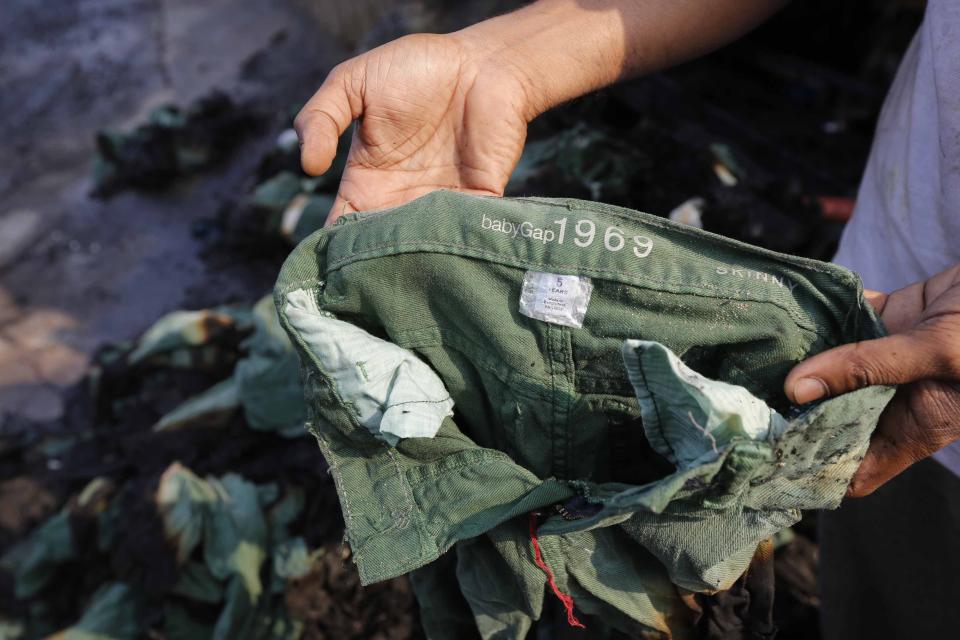 An employee shows the brand of a burnt clothing item in front of a Standard Group garment factory which was on fire in Gazipur