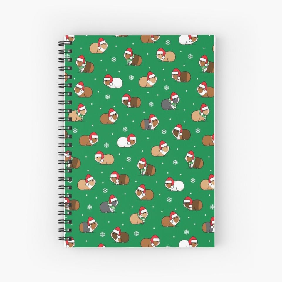 A notebook with a green cover with guinea pigs with santa hats on