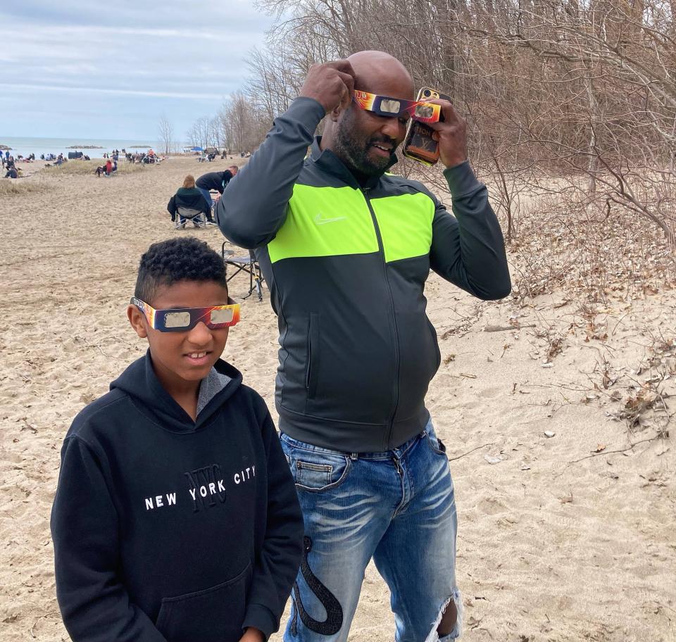 Dushawne Evans, at right, and his son 10-year-old Jayden Evans, try their eclipse glasses on for size Monday afternoon at Presque Isle State Park. They drove more than six hours from near Washington, D.C. The two are drone enthusiasts who purchased special filters to take photos of the event. “This is a once in a lifetime event.” The older Evans said. “We decided to go for it.”