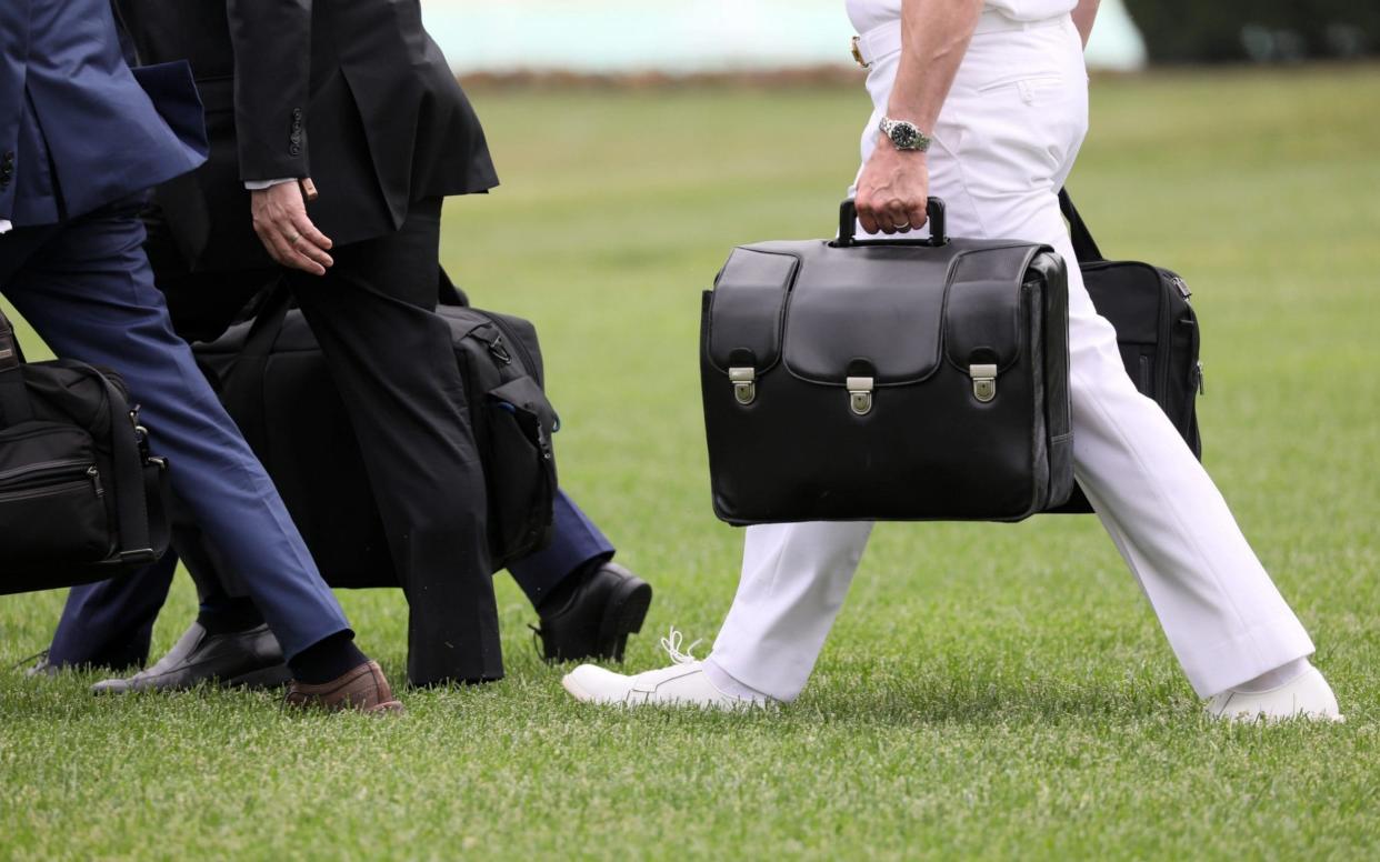 A military aide carries the nuclear "football" as he walks to board Marine One with President Trump  - Reuters