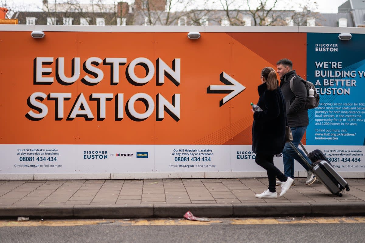 Members of the public walking past signs surrounding the construction site for the London Euston HS2 terminal (Aaron Chown/PA) (PA Wire)