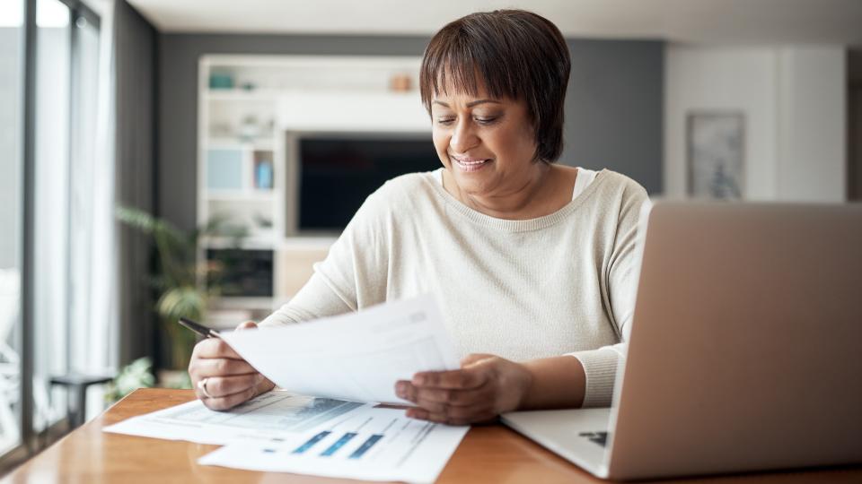 Cropped shot of a happy senior woman sitting alone in her living room and going through paperwork.