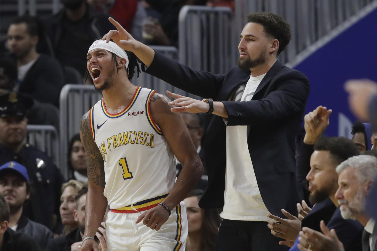 Injured Golden State Warriors guard Klay Thompson, right, and guard Damion Lee (1) react after Alec Burks scored during the first half of the team's NBA basketball game against the Minnesota Timberwolves in San Francisco, Monday, Dec. 23, 2019. (AP Photo/Jeff Chiu)