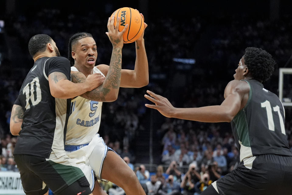 North Carolina forward Armando Bacot drives to the basket between Wagner guard Tahron Allen (10) and guard Melvin Council Jr. (11) during the first half of a first-round college basketball game in the NCAA Tournament, Thursday, March 21, 2024, in Charlotte, N.C. (AP Photo/Chris Carlson)