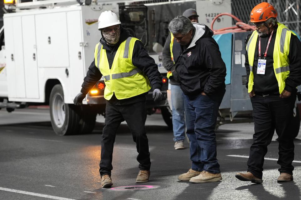 Workers examine a hole on the strip before the start of the second practice session for the Formula One Las Vegas Grand Prix auto race, Friday, Nov. 17, 2023, in Las Vegas. (AP Photo/Nick Didlick)