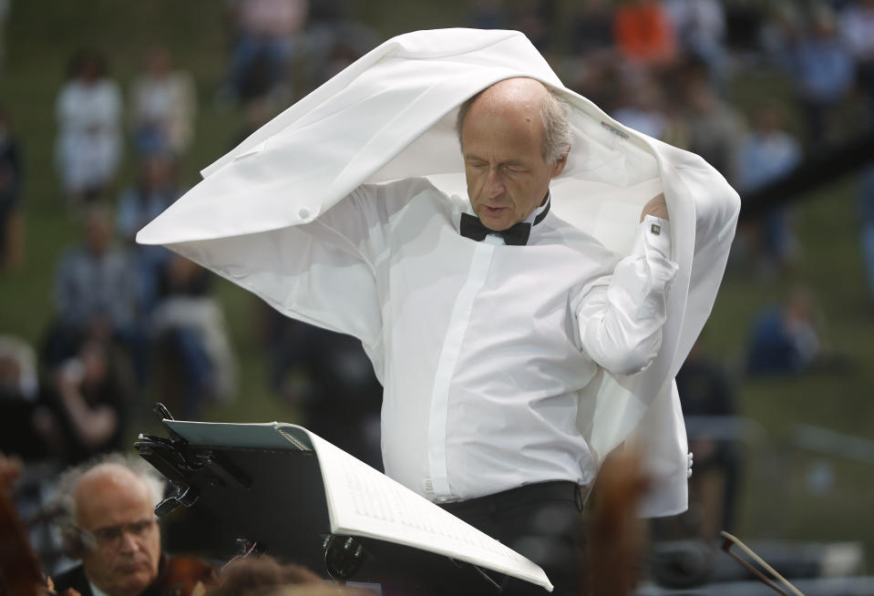 Ivan Fischer, founder of the Budapest's Festival Orchestra, adjusts his jacket after he received his third dose of the COVID-19 vaccine as he conducts the orchestra, during their free concert in Budapest, Hungary, Wednesday August 25, 2021. The Budapest Festival Orchestra promoted the need for booster shots and encouraged Hungarians to stay alert since the risk of becoming infected is still high as the delta variant spreads. AP Photo/Laszlo Balogh