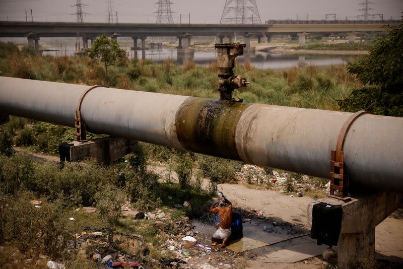 FILE PHOTO: A man bathes under a broken water pipeline on a hot summer day in New Delhi