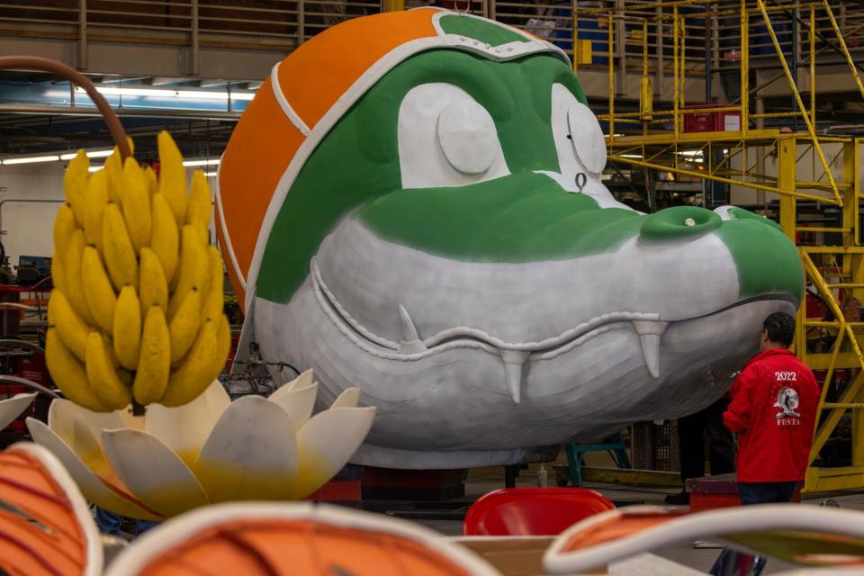 Andres Trujillo decorates an alligator sculpture on a float.