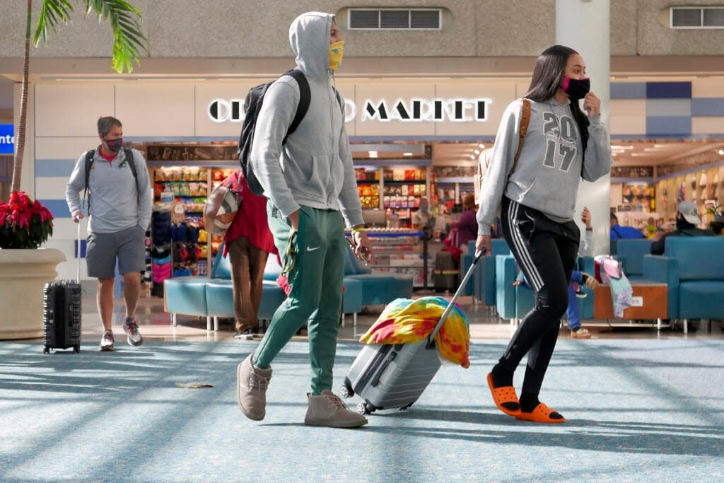 Holiday travelers make their way through Orlando International Airport Tuesday, Nov. 24, 2020, in Orlando, Fla. (AP Photo/John Raoux)