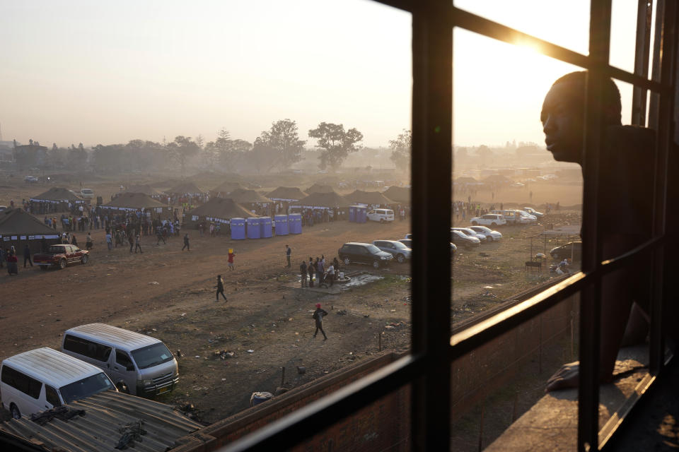 A man looks on from a building overlooking a polling station in Harare, Zimbabwe, Wednesday, Aug. 23, 2023. Polls have opened in Zimbabwe as President President Emmerson Mnangagwa seeks a second and final term in a country with a history of violent and disputed votes. (AP Photo/Tsvangirayi Mukwazhi)