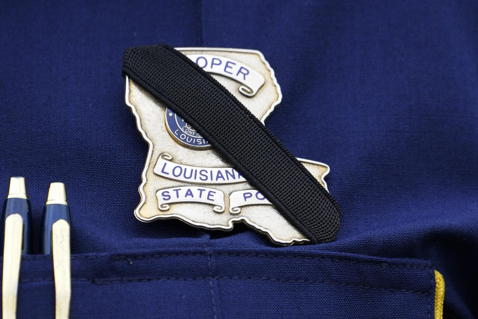 A black ribbon is placed across the badge of a trooper with the Louisiana State Police at the funeral services for Master Trooper Chris Hollingsworth, Friday, Sept. 25, 2020 in West Monroe, La. Hollingsworth, killed in a car crash hours after he was told he would be fired for his role in the death of a Black man, was buried with honors Friday at a ceremony that authorities sought to keep secret out of concerns it would attract a mass protest. (AP Photo/Rogelio V. Solis)