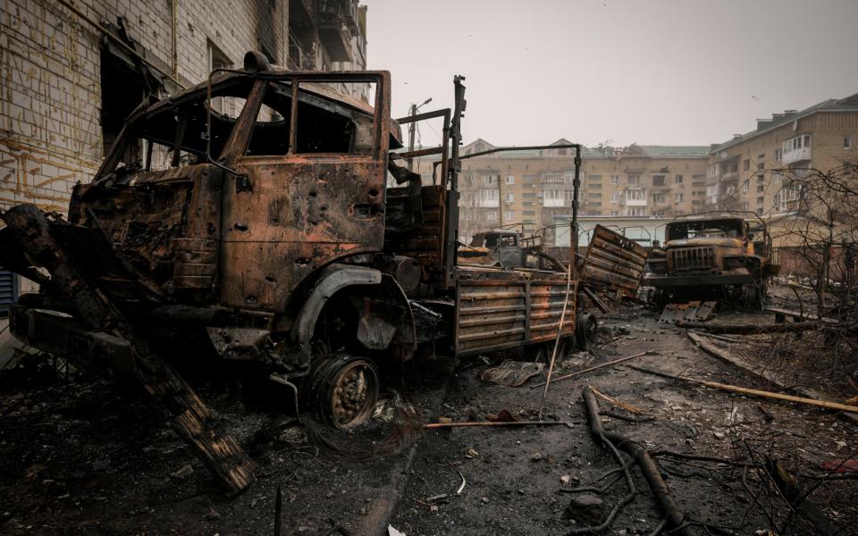 Russian military trucks, destroyed during fighting between Russian and Ukrainian forces, are backdropped by a heavily damaged apartment building outside Kyiv, Ukraine - Vadim Ghirda/AP