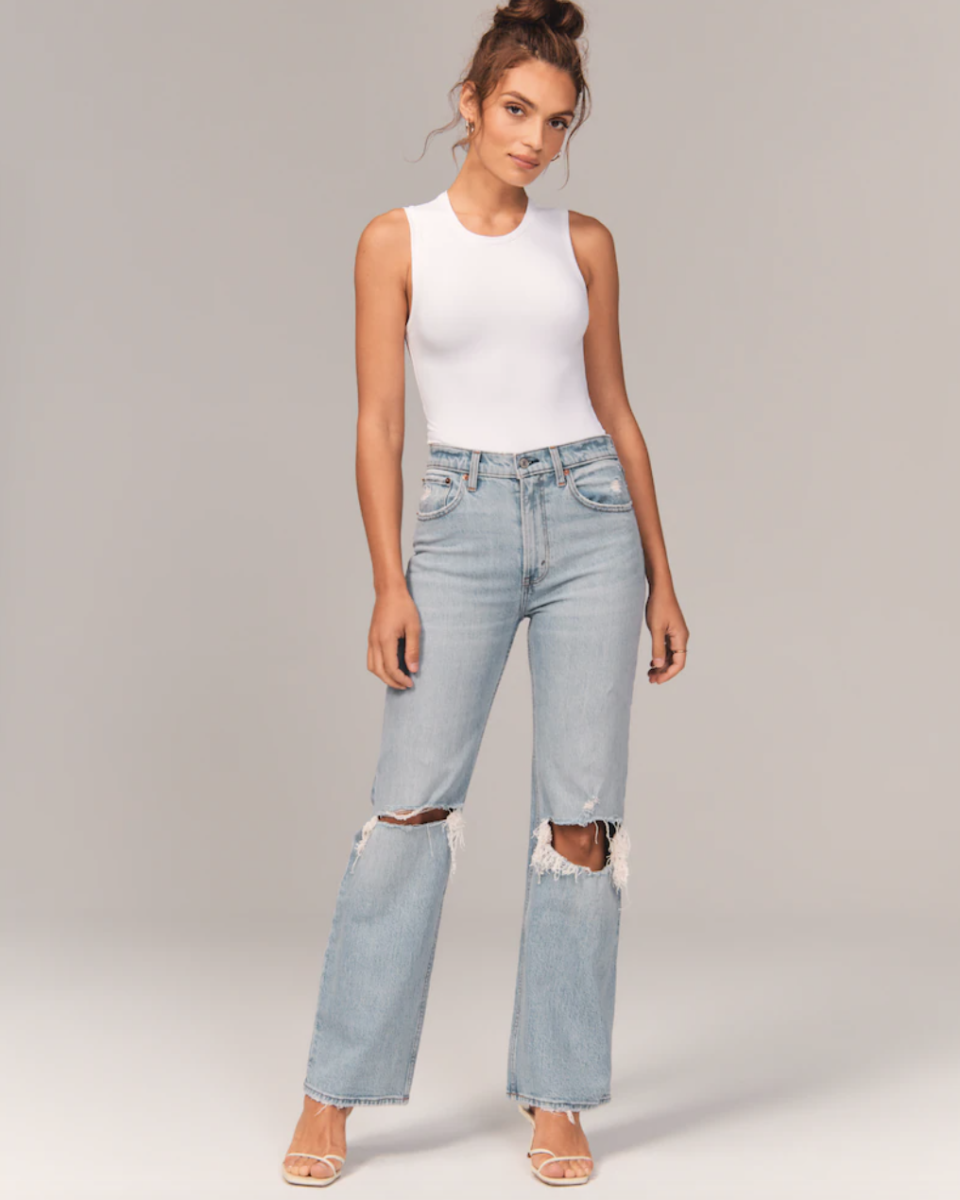 model in high bun, white bodysuit and ripped jeans High Rise 90s Relaxed Jean (Photo via Abercrombie)