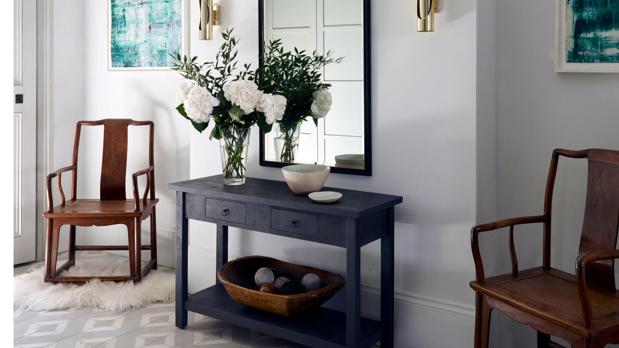  console table and mirror with wooden armchairs in entryway 