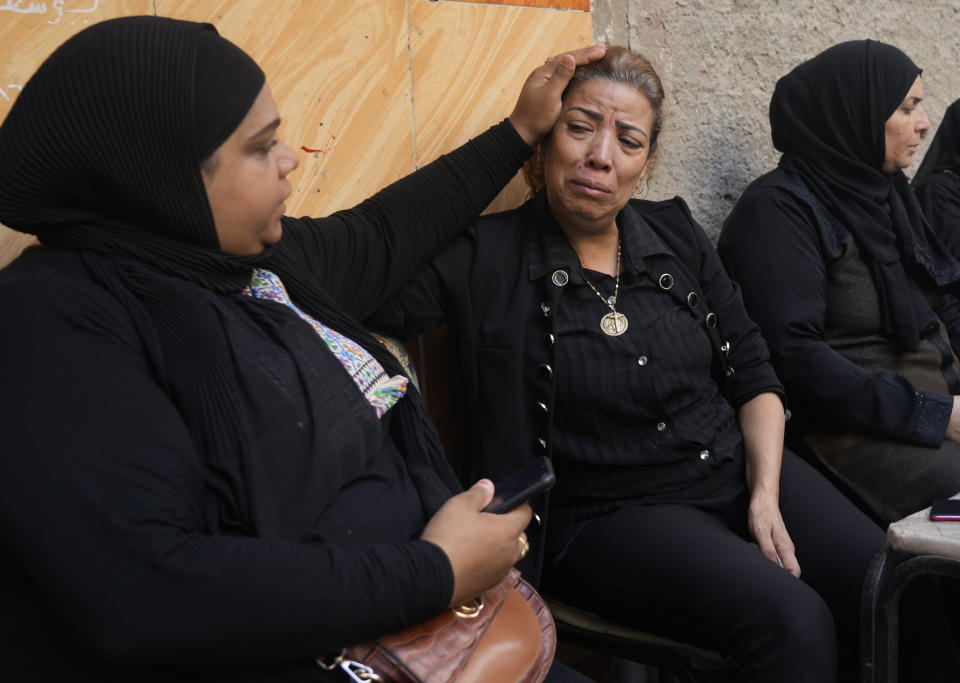 FILE - Mariam Habeib, center, who lost 6 relatives in a fire at the Abu Sefein Coptic Orthodox church that killed 41 people earlier this month, receives condolences from Muslim neighbors outside her house in the Imbaba neighborhood of Giza, Egypt, Aug. 16, 2022. The tragedy struck a community that of Christians that is one of the world’s oldest, but that is also no stranger to sadness. A minority in Egypt, Coptic Orthodox Christians have faced deadly attacks by Islamist extremists, restrictions on church building, and outbursts of sectarian-motivated violence in recent decades. (AP Photo/Amr Nabil, File)