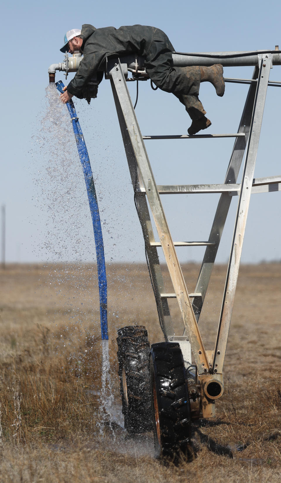 Tyler Black attaches a new sand drain on the end of a pivot on his Muleshoe, Texas, farm on Monday, April 19, 2021, as he prepares to plant grass in a pasture. Black raises cattle and plants pasture in wheat and some native grass – and rations water use -- because the Ogallala Aquifer is being depleted. (AP Photo/Mark Rogers)