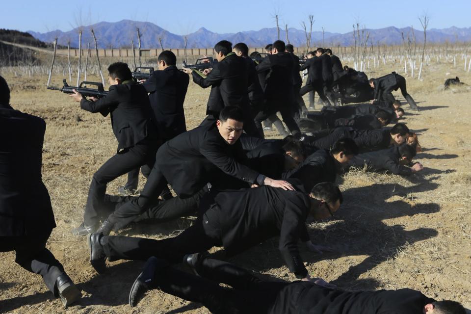 Students holding replica 95 semi-automatic rifles practice protecting their employers at a shooting training field managed by the military during the Tianjiao Special Guard/Security Consultant training on the outskirts of Beijing